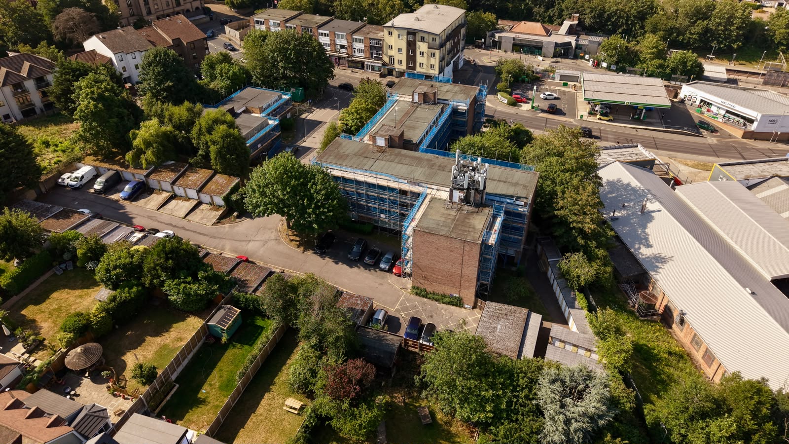 Wide drone view of scaffolded residential blocks within a town centre