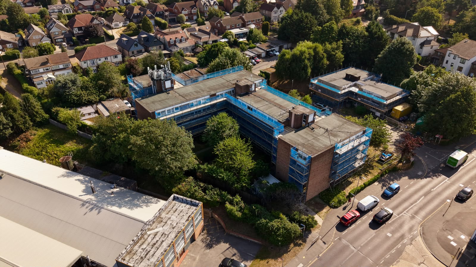 Aerial view of blue-netted scaffolding wrapping an L-shaped apartment block