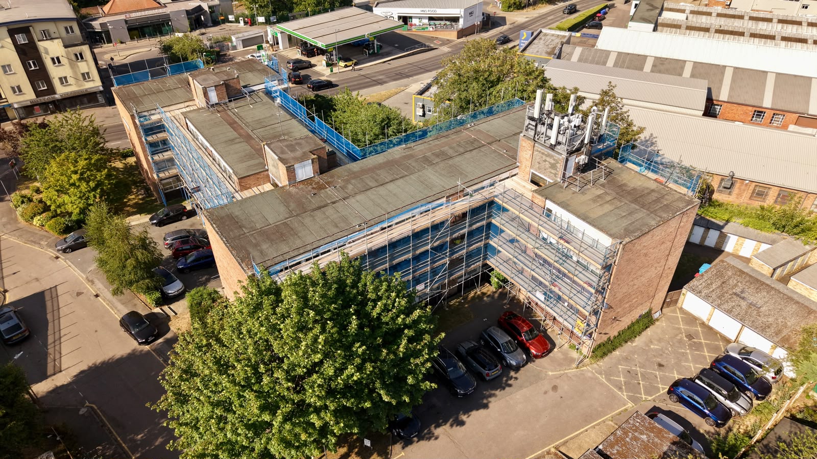 Aerial view of scaffolding to a four-storey block of flats beside a parade of shops