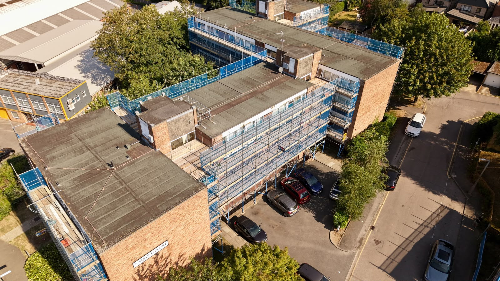 Drone photograph of a boarded scaffold lift along the front elevation of a flats block