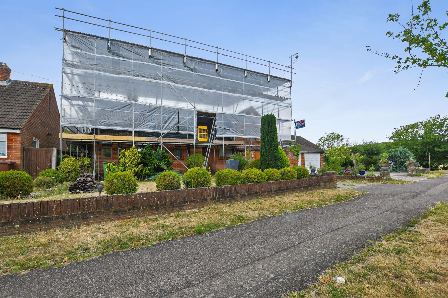 Sheeted temporary roof scaffold protecting a residential property during re-roofing